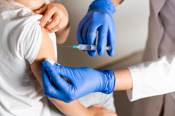 vaccination of children, a little girl at a doctor's appointment, an injection in the arm, the conce, close-up
