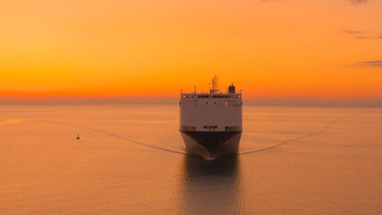 AERIAL: Golden summer evening sky spans above a freight ship transporting goods