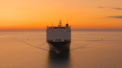 AERIAL: International cargo ship transporting merchandise on a sunny evening.
