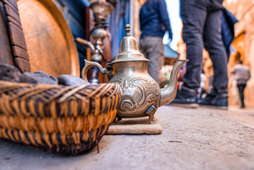 Vintage decorated teapot on display for sale on street in market, Ancient teapot beside basket at market