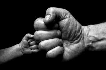 Grayscale closeup of a grown man's hand fist-bumping with a child's hand