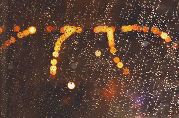 Rain drops on the window against bokeh lights. Shallow depth of field, abstract background