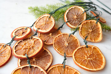 Close-up of handmade Christmas garlands out of dried orange slices on marble surface