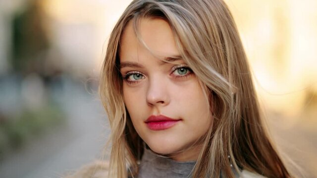 Closeup face of beautiful blond smiling woman with long hair. Portrait of gorgeous girl looking to camera