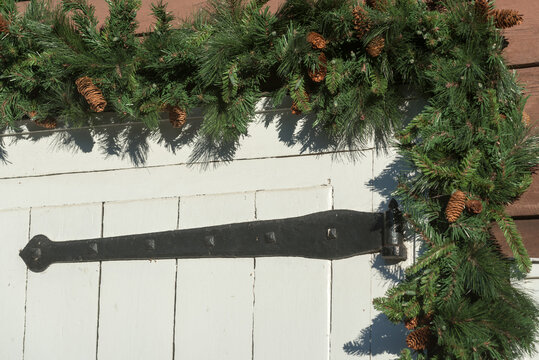 Fake Christmas Garland And Lights Around A Barn Door With Black Hinge 