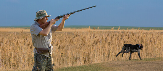 Hunter man in camouflage with a gun during the hunt in search of wild birds or game. Autumn hunting...