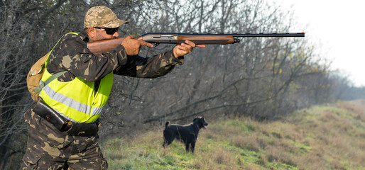 Hunter man in camouflage with a gun during the hunt in search of wild birds or game. Autumn hunting season.