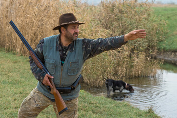 Hunter man in camouflage with a gun during the hunt in search of wild birds or game. Autumn hunting...