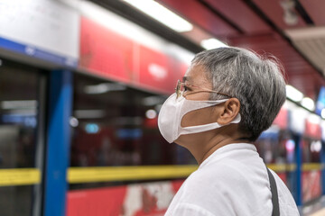 Asian traveler senior woman wearing face mask at gate metro or subway train feeling alone while...