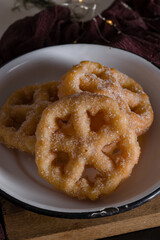 Delicious fritters on a white plate, on top of a piece of wood, a common Mexican dessert to celebrate festivities.