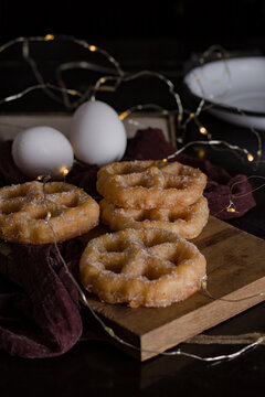 Photograph of donuts with sugar, in December times, with lights in the background, with a blue cloth and colored stripes, representing Mexico, in the photo there are also two eggs and a white plate.