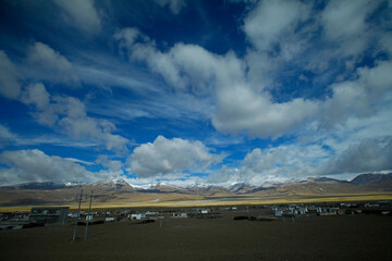 Fototapeta na wymiar The blue sky white clouds and grassland snow mountain landscape