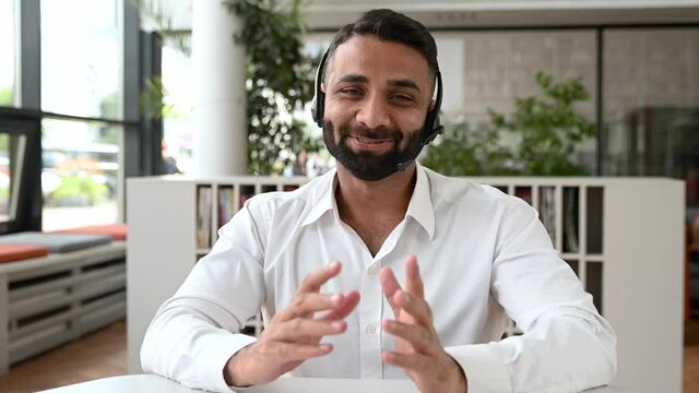 Friendly confident sociable Indian businessman, top manager, financial consultant, in office, communicating with colleagues through online communications, gesturing with his hands, discuss strategy