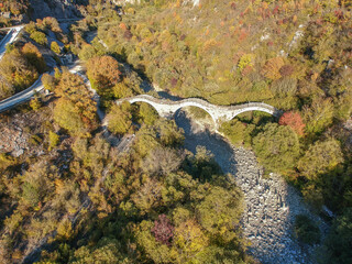 Aerial view of old Kalogeriko triple arched stone bridge on Vikos canyon, Zagorohoria, Greece, Europe