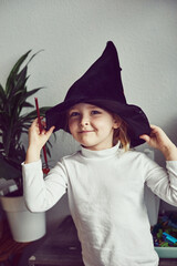 Naughty and sly preschooler girl ready to cast a magic spell. Little girl playing wizarding world...