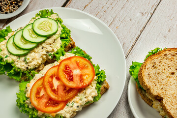 Homemade egg salad sandwich with wholewheat bun,cucumber, tomatoes,lettuce,egg,and cream cheese.  Rustic style. Selective Focus. Top view. Copy space. No.08