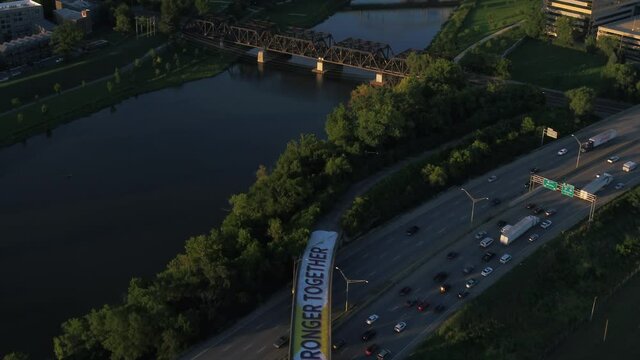 Aerial view over traffic on I 71, revealing the sunny evening skyline of Columbus, USA - tilt, drone shot