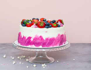 Delicate cake decorated with fresh berries, strawberries and blueberries on a light plain background