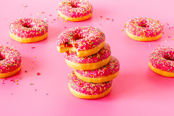 Group of pink frosted donuts with colorful sprinkles