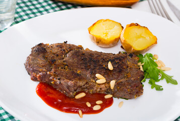 Barbecue rib steak served with ketchup, pine nuts and arugula