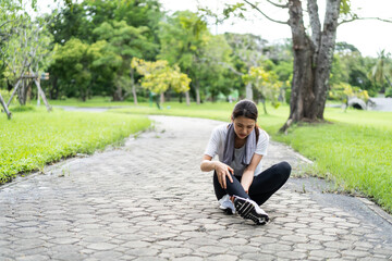 Fototapeta na wymiar Asian attractive sport woman feels pain on ankle while run on street.