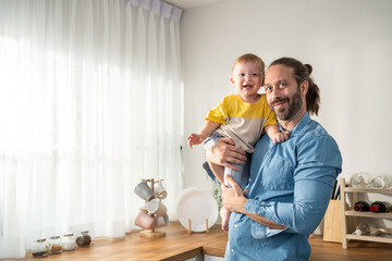 Portrait of Caucasian loving father hold baby boy child in living room