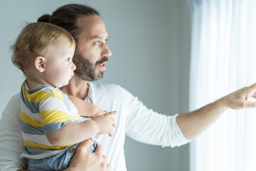 Fototapeta premium Caucasian loving father holding young baby boy child in living room.