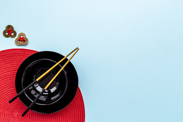 Fototapeta na wymiar Black and gold chopsticks with red mat. Asian tabble place setting