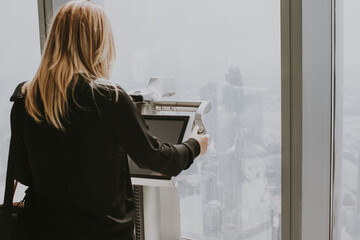 Woman tourist using a digital electronic telescope at the observation deck