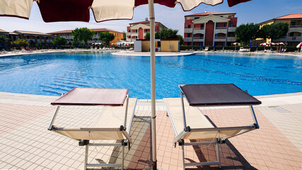 Fototapeta premium Lounge summer. Resort chair, relax lounge at hotel pool. Beach lounger chaise. Vacation sunbed. Luxury travel poolside concept.
