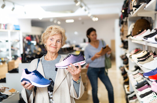 Portrait of a mature european woman in a shoe store holding sports sneakers in her hands