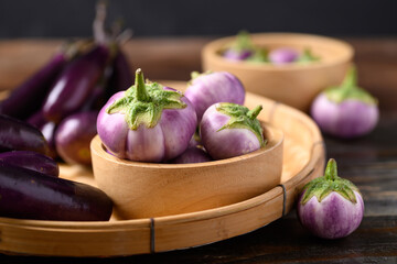 Fresh organic Thai purple eggplant in small basket on wooden background, Food ingredient