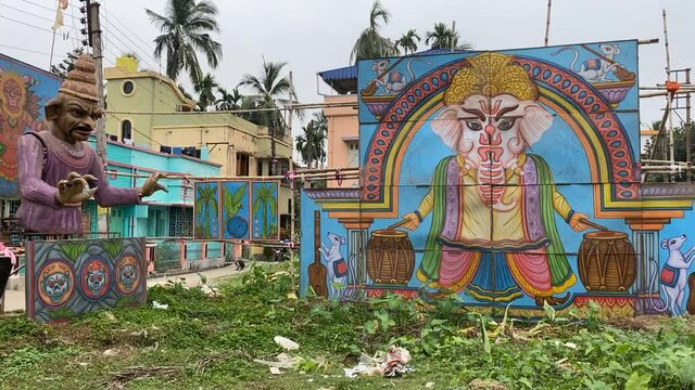 Slow motion shot of the cutouts and lightnings done during the puja pandal festival celebration in a natural morning background view with houses and trees in the back of the cutouts on the side.