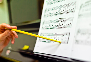 Close-up of a hand holding a pencil on paper at a piano lesson 