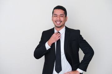 Adult Asian man wearing black suit showing high confidence with hand touching his tie