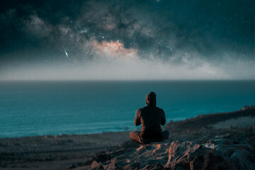 person meditating at night on top of the mountain under the Milky Way and shooting star	