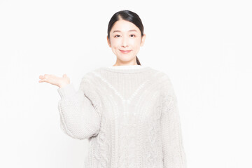 白い背景の前に立って案内をするセーターを着ている主婦
