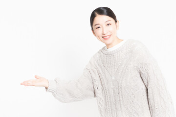 白い背景の前に立って案内をするセーターを着ている主婦