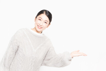 白い背景の前に立って案内をするセーターを着ている主婦