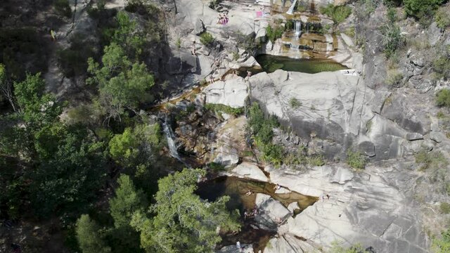 People relaxing in clear waters of natural pool at Cascatas de Fecha de Barjas, Portugal. Aerial circling