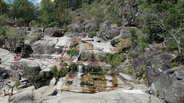 People relaxing on rocks at Cascatas de Fecha de Barjas in Peneda-Geres National park, Portugal. Aerial rising