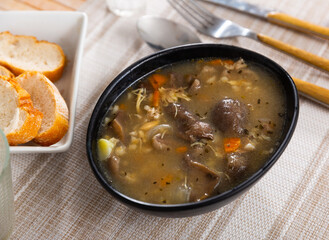 Bowl of mushroom soup with pork meat, potato, carrot, onion and dried herbs