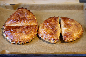 4 Cornish pasties on a baking tray with paper hot out of oven. Selective focus