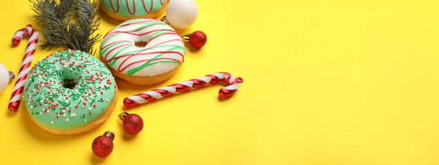 Tasty Christmas donuts and decorations on yellow background with space for text