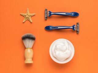 A set of stylish modern accessories for men's shaving on an orange background. Flat lay.