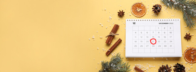 Calendar with marked date of winter solstice and decorations on color background with space for text