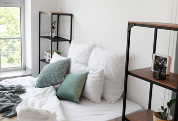Big comfortable bed and shelving units near light wall