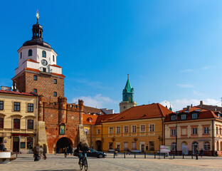 Picturesque Lublin cityscape with historic symbol of city - medieval brick gate Brama Krakowska in sunny spring day, Poland - obrazy, fototapety, plakaty