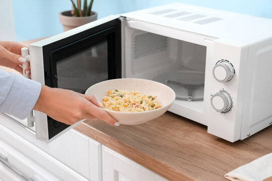 Woman heating food in microwave oven