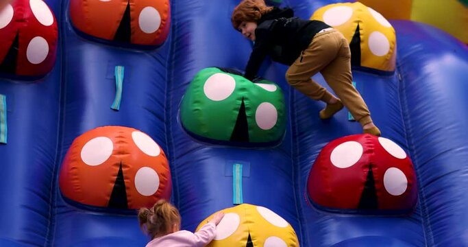 kids having fun on inflatable playground, climbing the colorful wall at the amusement park